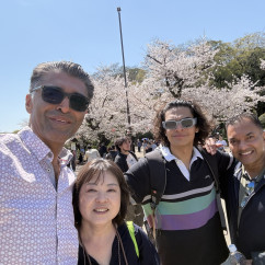 Friends gather under blooming trees, smiles bright in the sunlight.