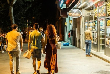 Tourist couple walking hand in hand along a quiet street at night in Madrid with a local guide