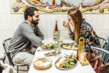 Couple of tourists enjoying a meal and wine at a local restaurant on a food tour of Lisbon