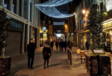 Local guide walking down a street in Edinburgh with a tourist while on a night tour of the city