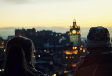 Couple of tourists looking out over Edinburgh at dusk