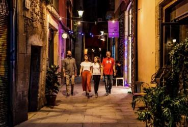 Local guide walking with a group of tourists through a quiet alleyway on a night out in Barcelona