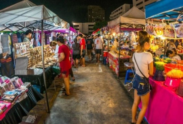 Tourists and locals browsing a busy night market in Bangkok