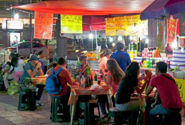 Tourists dining at a typical street-side eatery on a night tour of Mexico City with a local