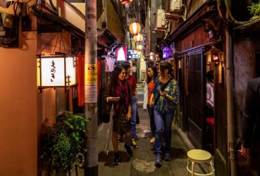 Tourists walking down a small alleyway with a local guide on a night tour of Tokyo
