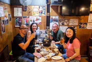 Local guide enjoying drinks and local cuisine at their favorite izakaya with tourists on a night out in Tokyo
