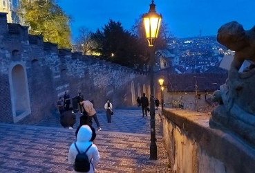 Tourists walking down old castles steps at night in Prague