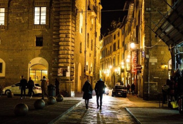 Tourists walking down a quiet street in Florence at night