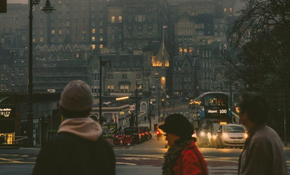 Tourists and a local guide walking along a street in Edinburgh at night