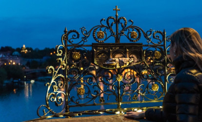 Tourist looking at the love locks on Charles Bridge while exploring Prague on a night tour