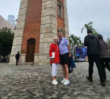 The historic Clock Tower in Hong Kong surrounded by pedestrians.