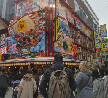 Street scene with people in front of Shinsekai district shopfront, Osaka, Japan.