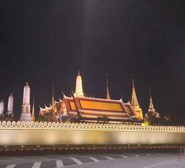 Temple of the Emerald Buddha at night with illuminated spires and wall.