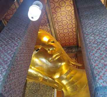 Reclining Buddha statue at Wat Pho, Bangkok, viewed from the side.