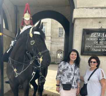 Two women pose near a mounted guard at Horse Guards Parade, London.