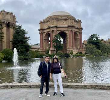 Strolling by the historic architecture, they pause to enjoy the view.