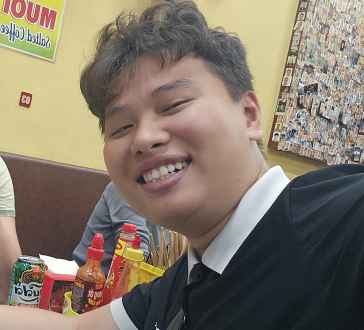 Woman and man posing for a selfie inside a small eatery.