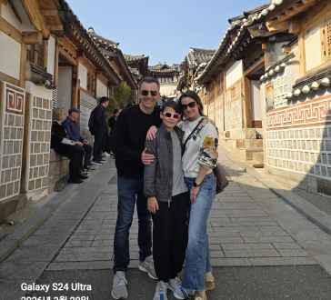 Three people stand on a traditional street in Seoul.