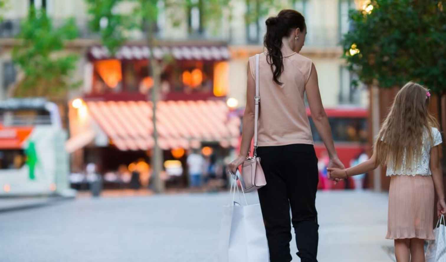 A woman and child walk hand in hand on a Parisian street.