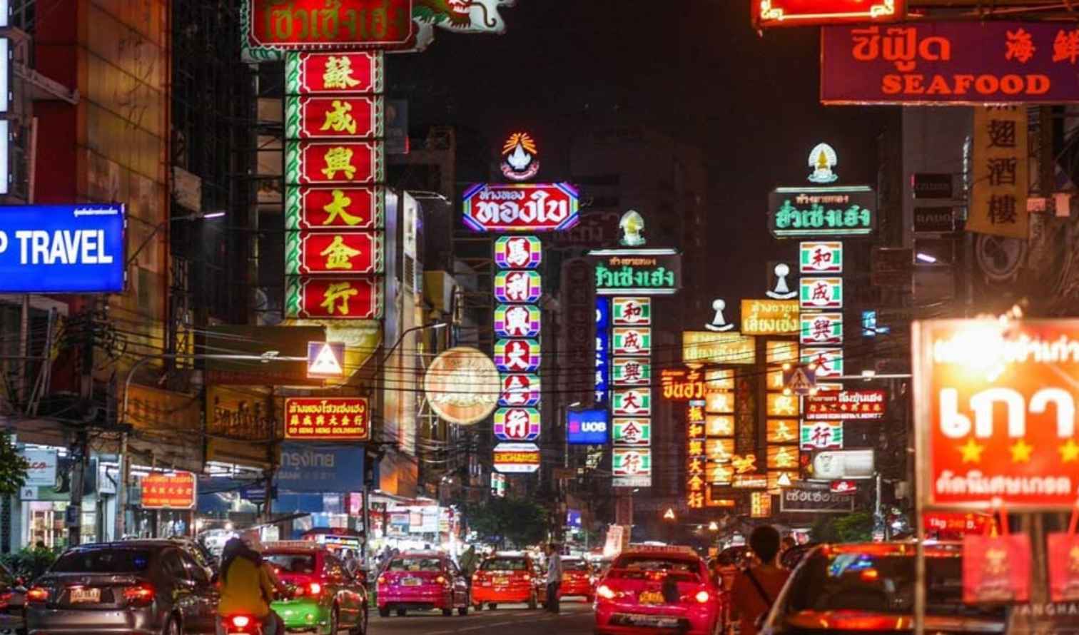Night view of Yaowarat Road in Bangkok with bright neon signs.