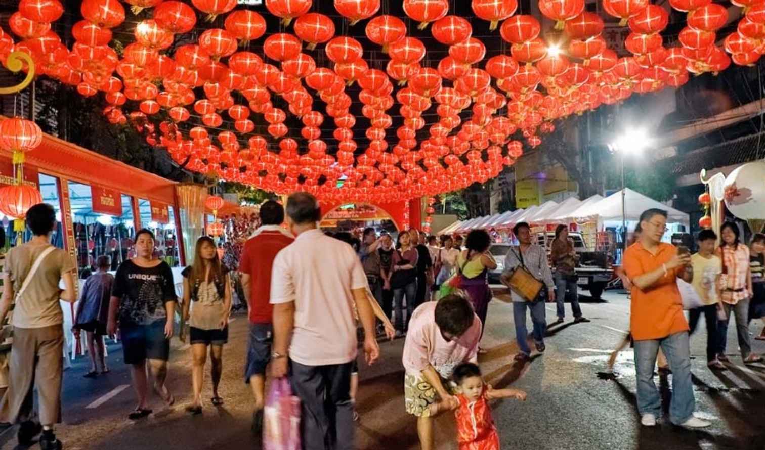 People walking under red lanterns on Yaowarat Road, Bangkok.