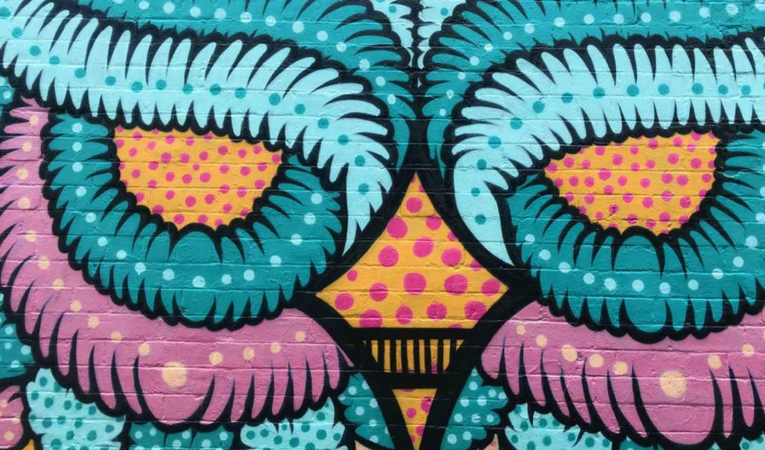 Close-up of owl street art with pink and blue patterns in Sydney