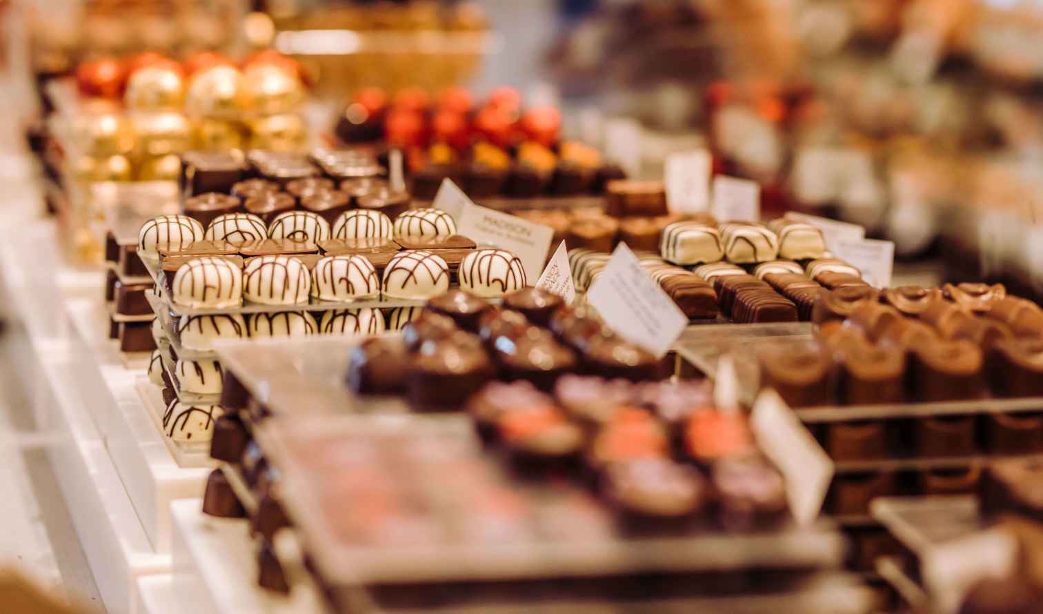 Rows of assorted chocolates displayed on trays in a shop in Brussels