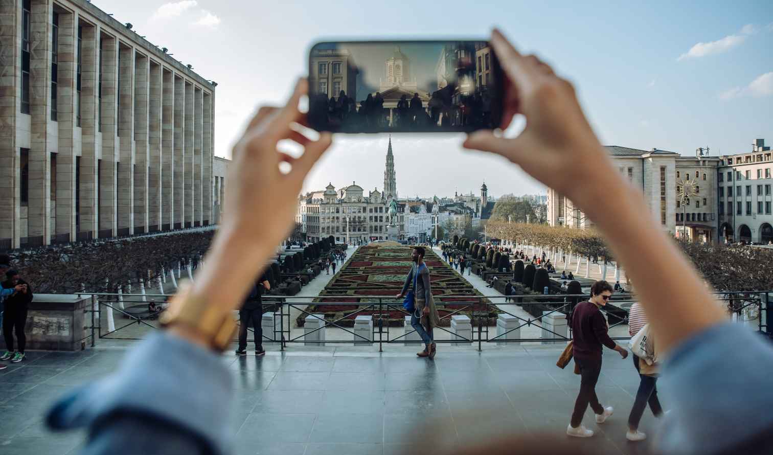 People walking in Mont des Arts, Brussels, with a smartphone capturing the view.