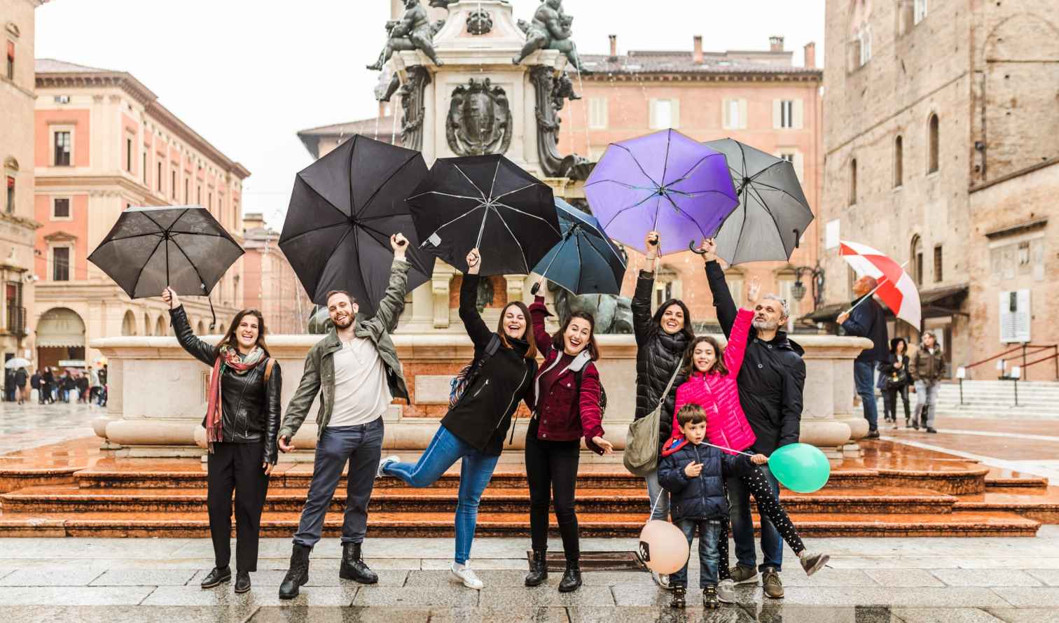 Group with umbrellas at the Fountain of Neptune in Bologna, Italy.