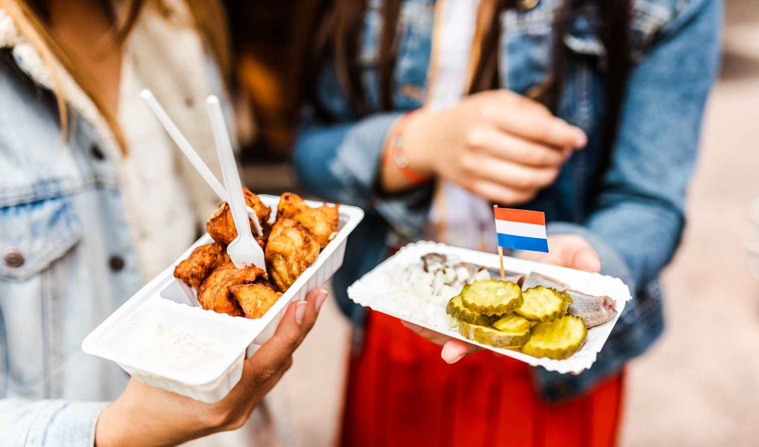 Hands holding Dutch street food with a Netherlands flag toothpick in Amsterdam