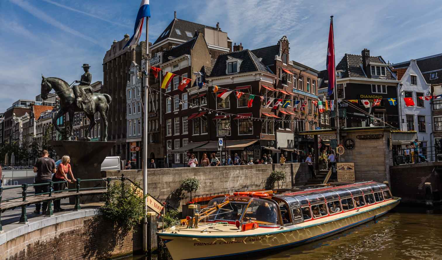 View of a canal in Amsterdam with a boat passing by.