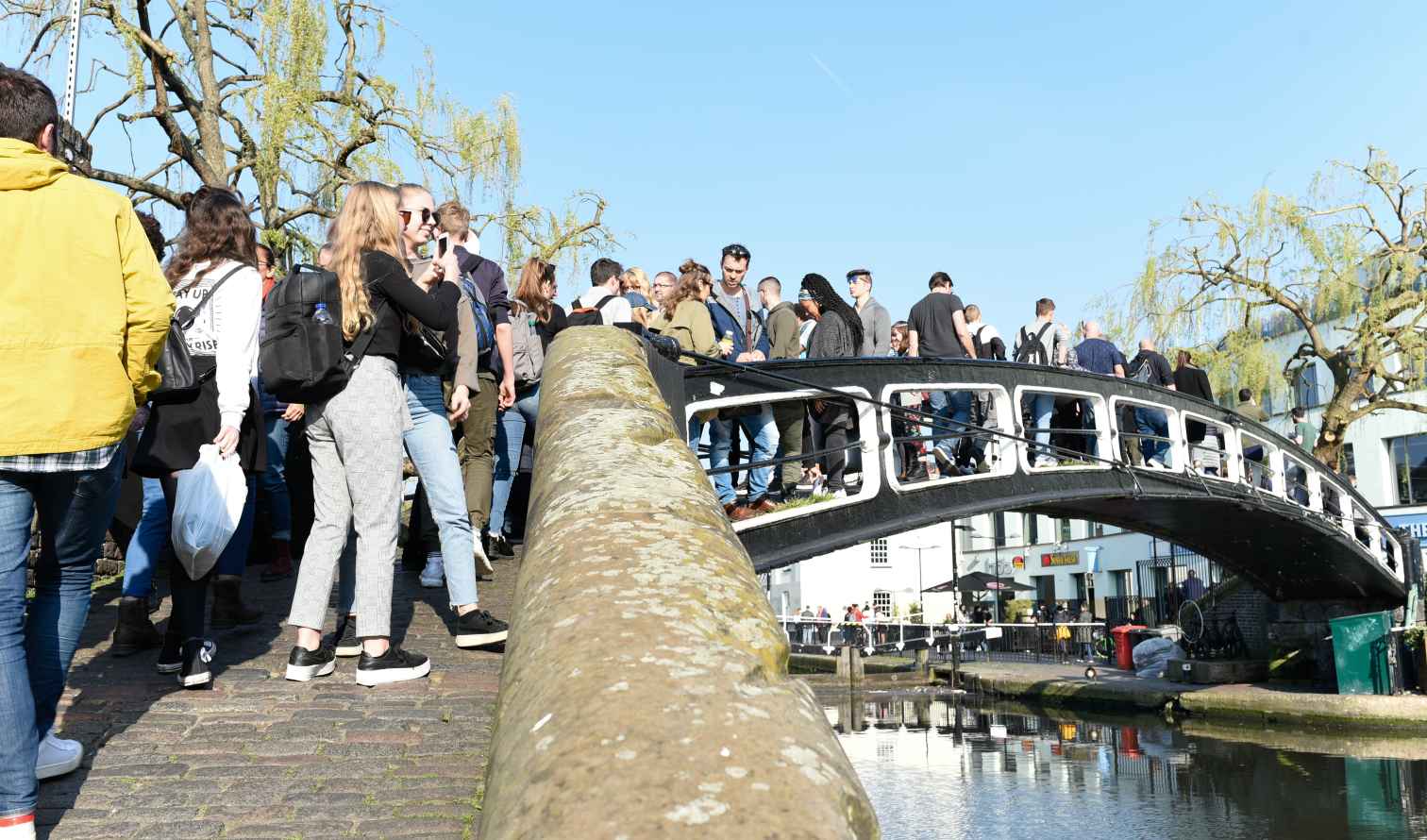 People crossing a pedestrian bridge in Camden Market, London.