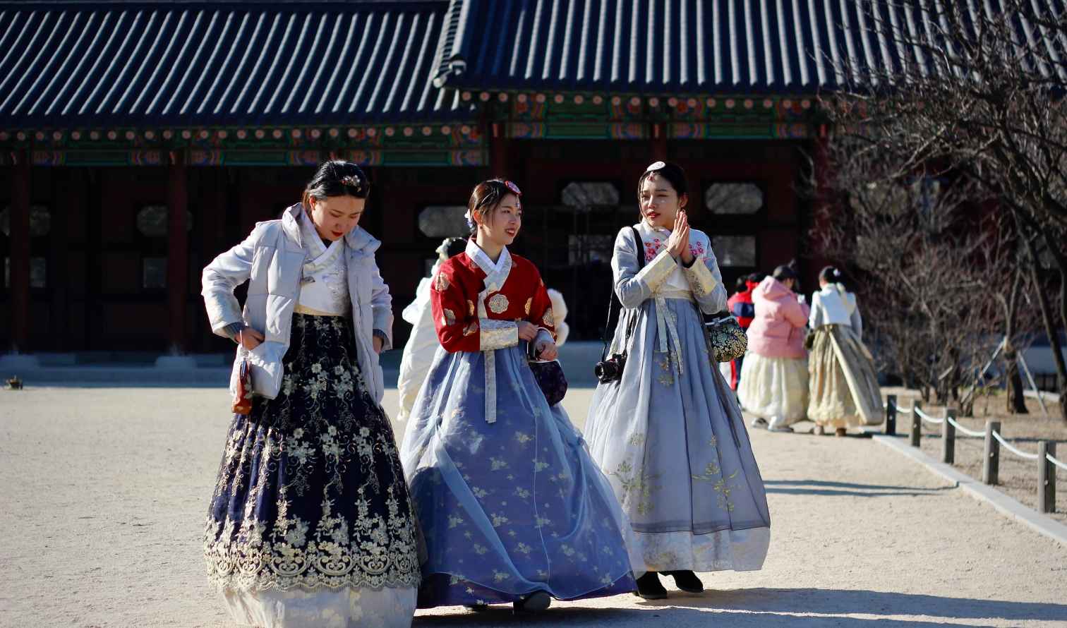 Women in hanbok stand in front of Gyeongbokgung Palace building in Seoul
