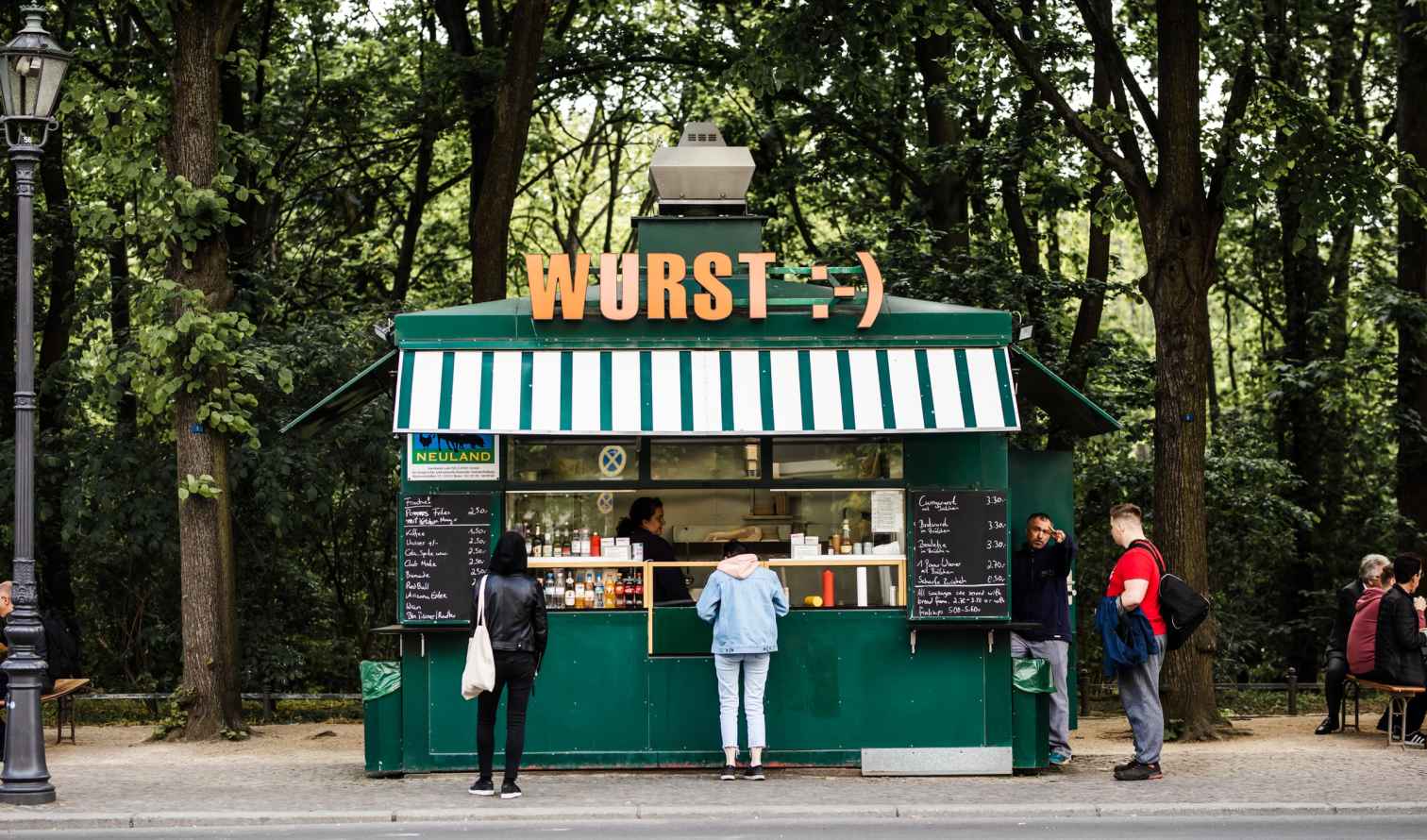 Food stand named 'Wurst' in a park setting with trees in Berlin