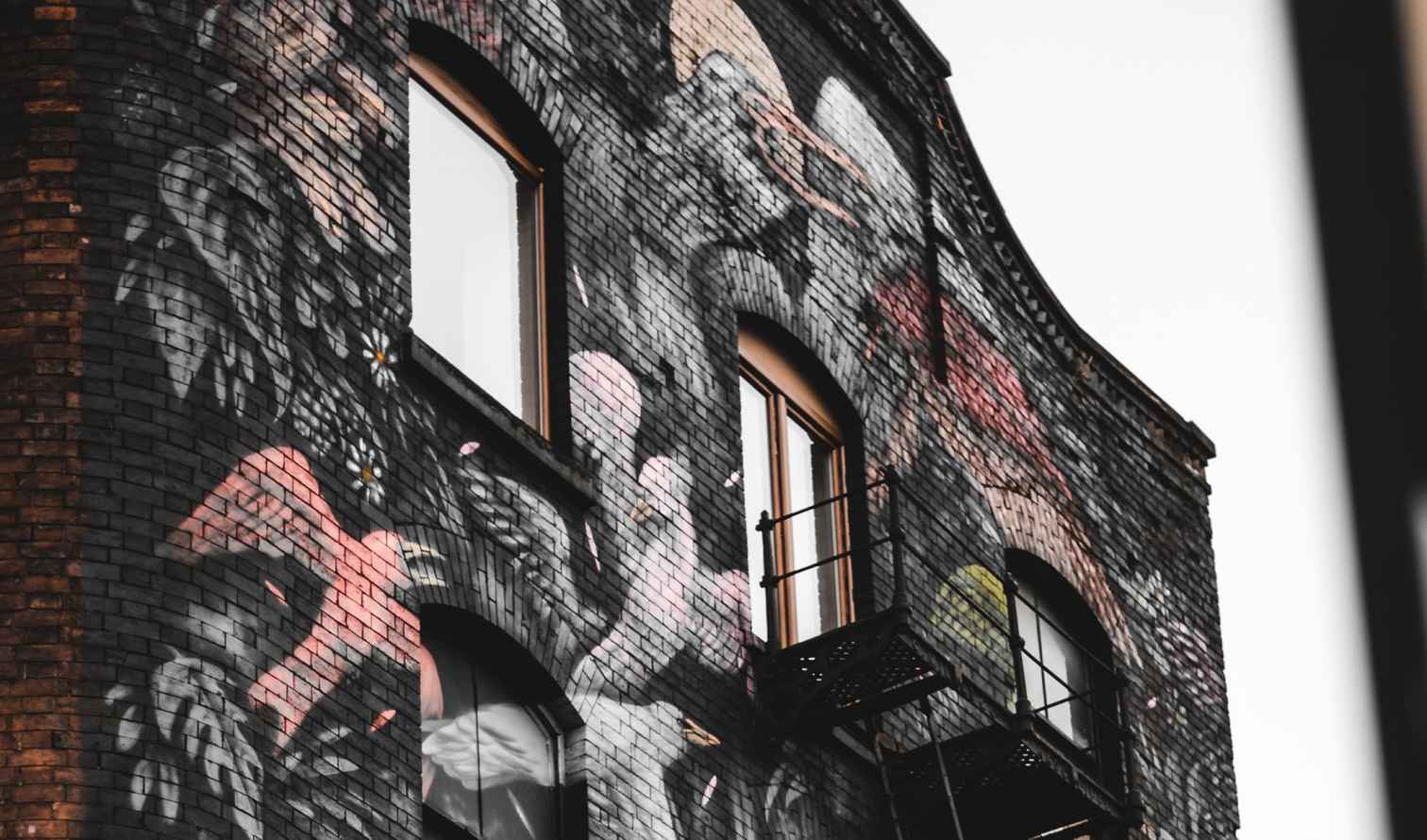Brick building with colorful graffiti of birds and flowers in Manchester