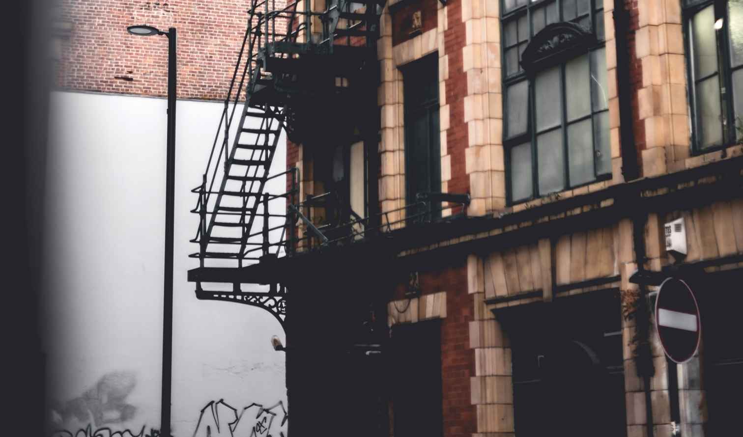 Exterior of a brick building with a fire escape ladder in Manchester.