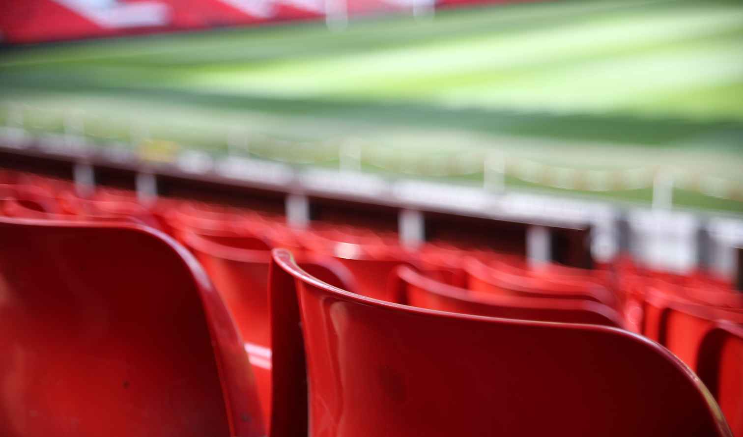 Unoccupied red seats with a view of the blurred pitch in Manchester