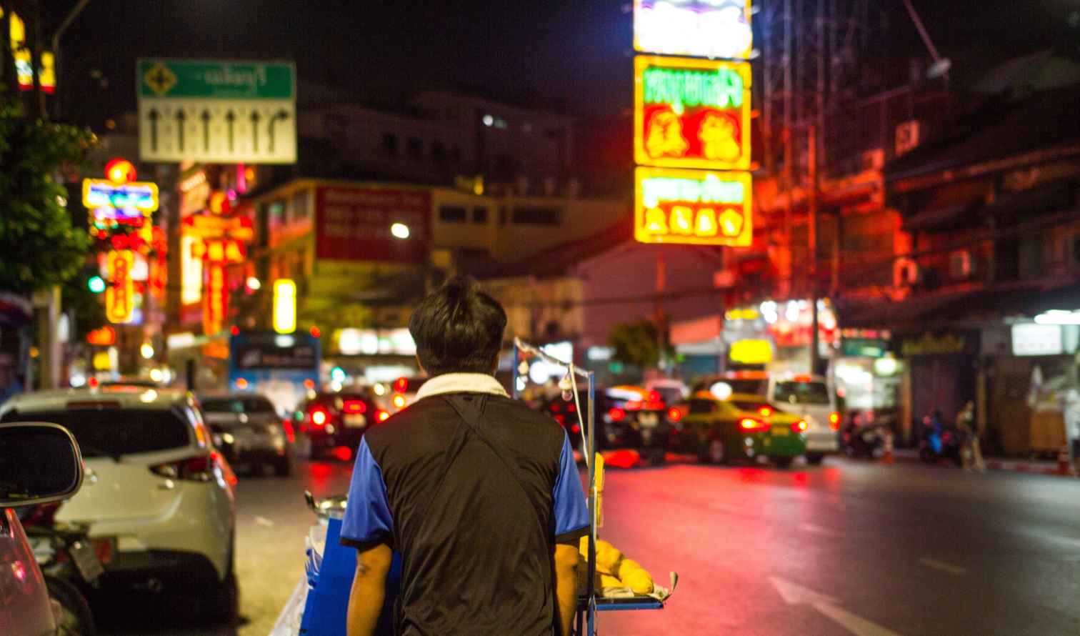 Person pushing a food cart on a busy street in Bangkok's Chinatown.