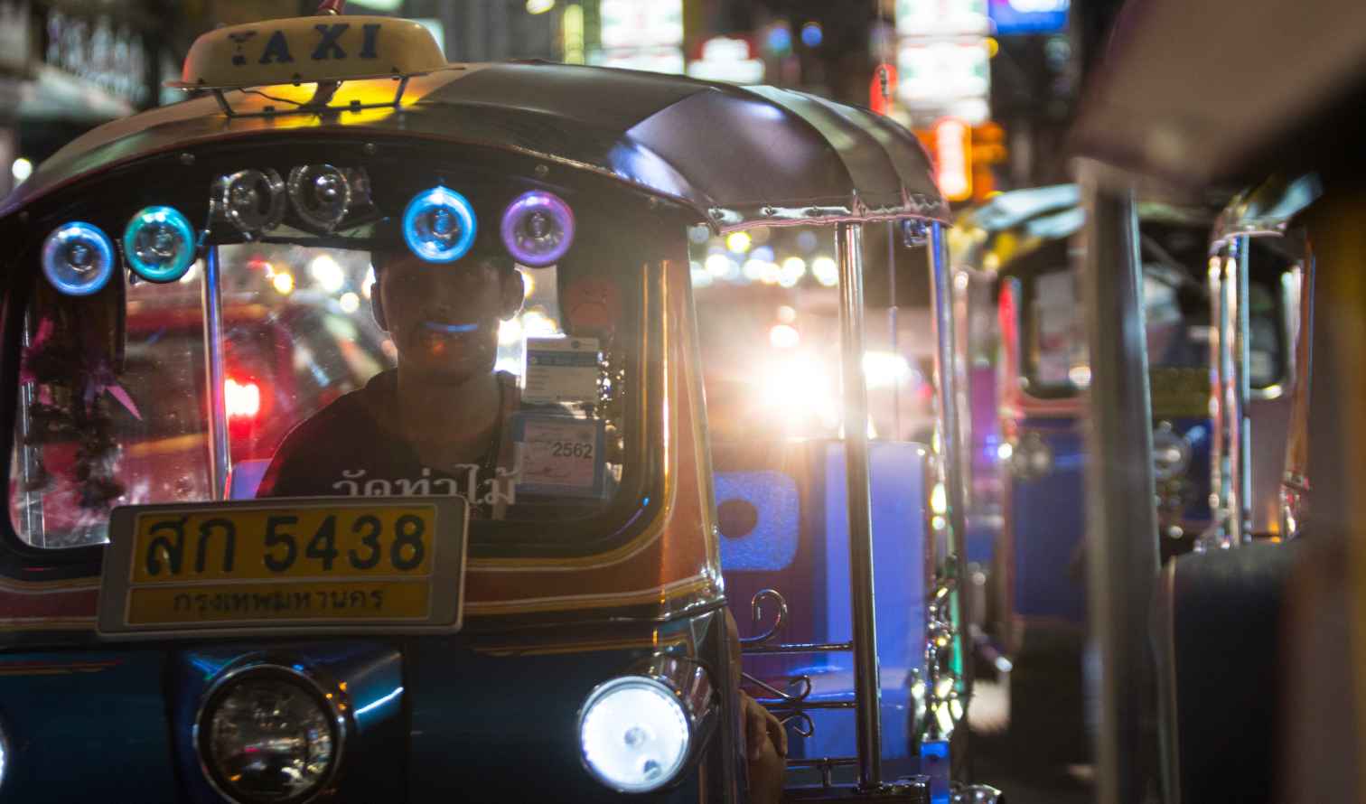 A tuk-tuk with a taxi sign in Bangkok at night.