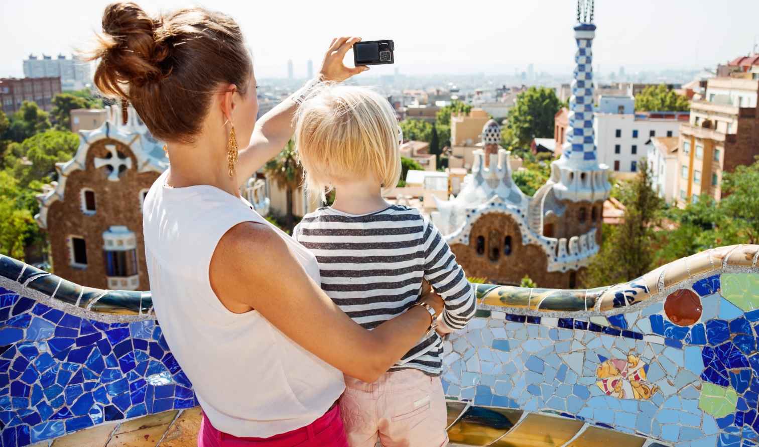 A woman and child at Park Güell with Barcelona skyline in background.