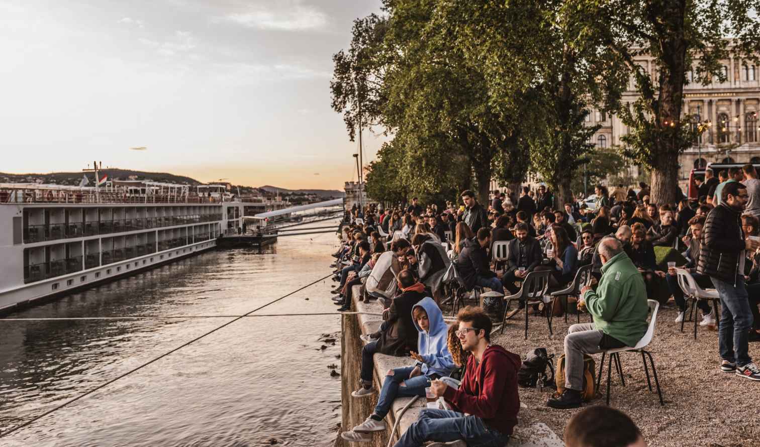 People sitting along the Danube River in Budapest, Hungary.