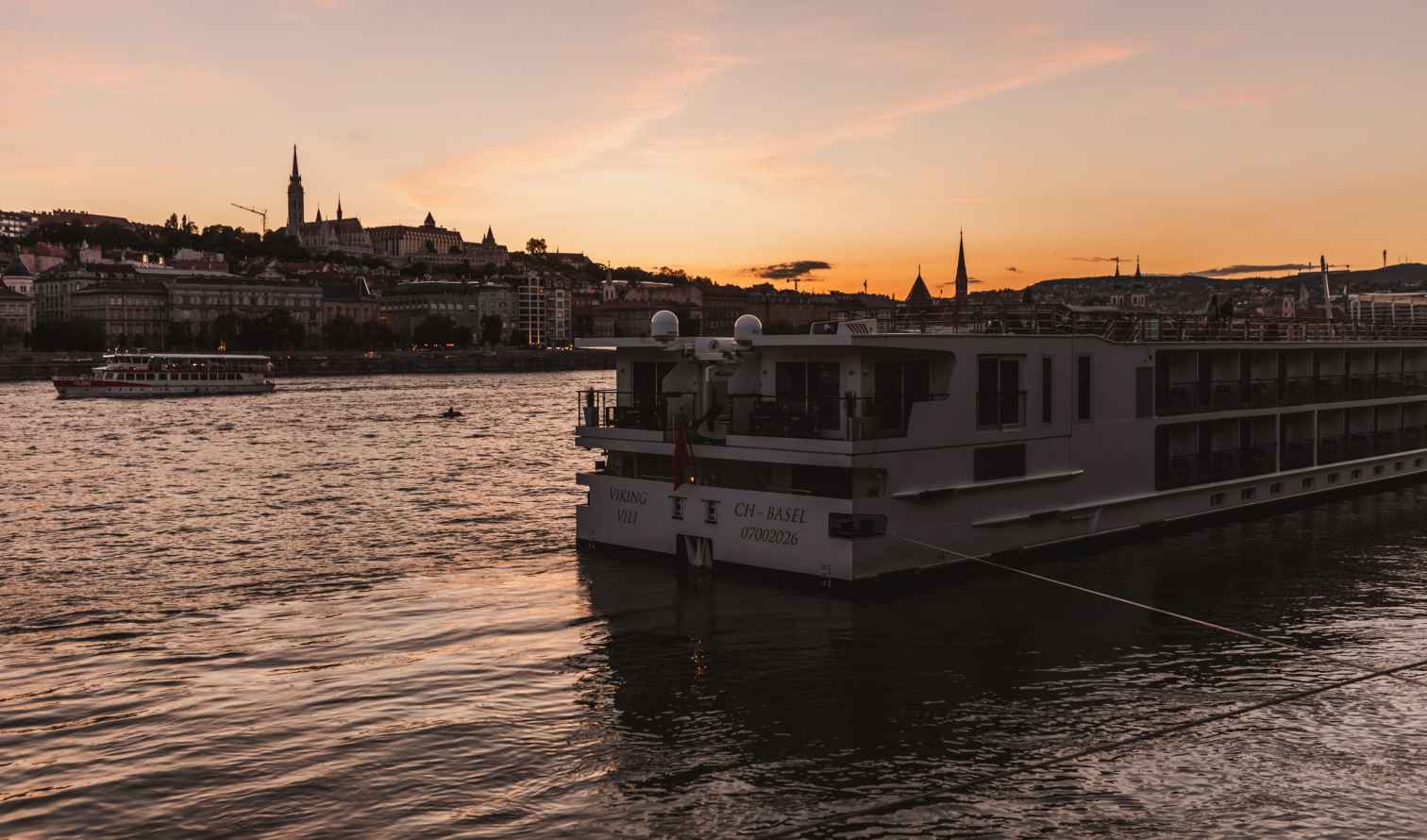 A river cruise ship docked on the Danube in Budapest at sunset.
