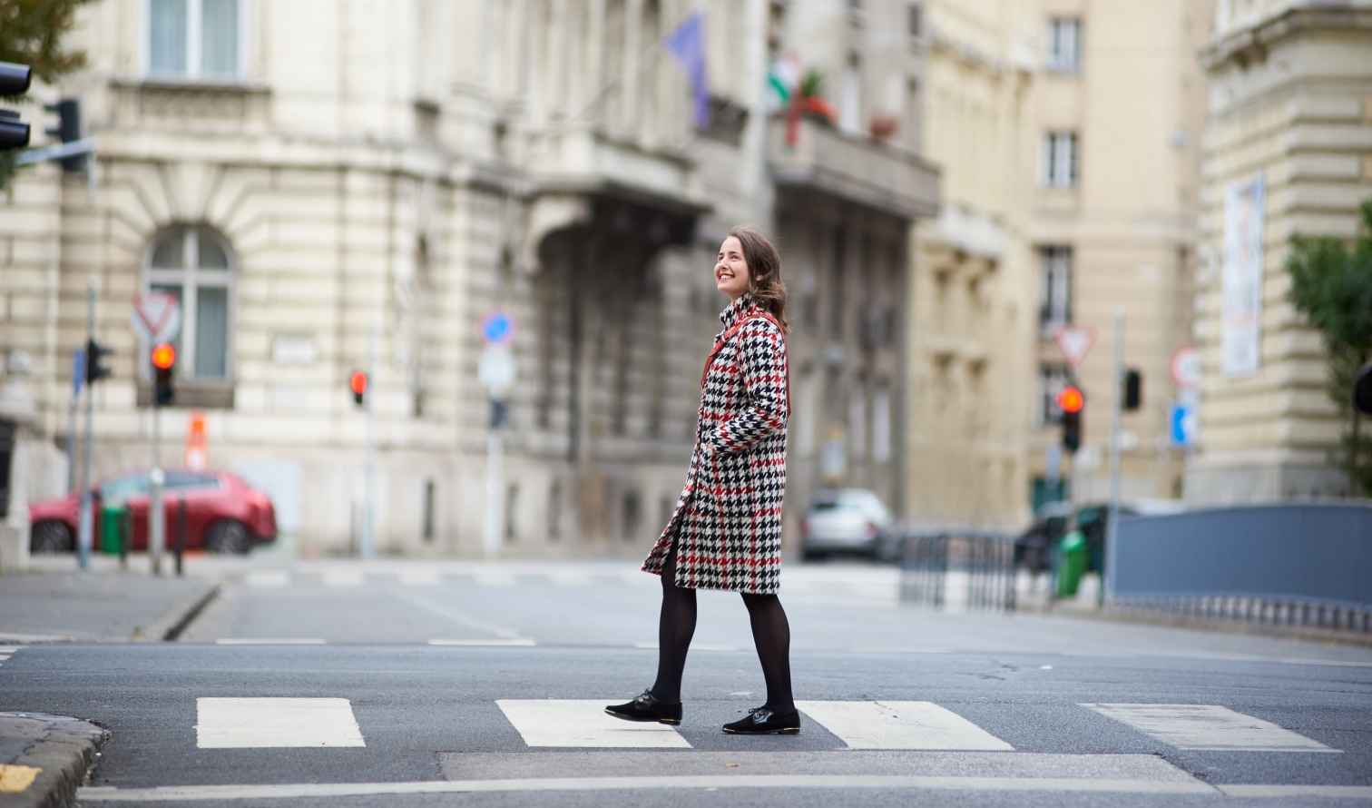 Woman crossing a street with historical buildings in Budapest, Hungary.