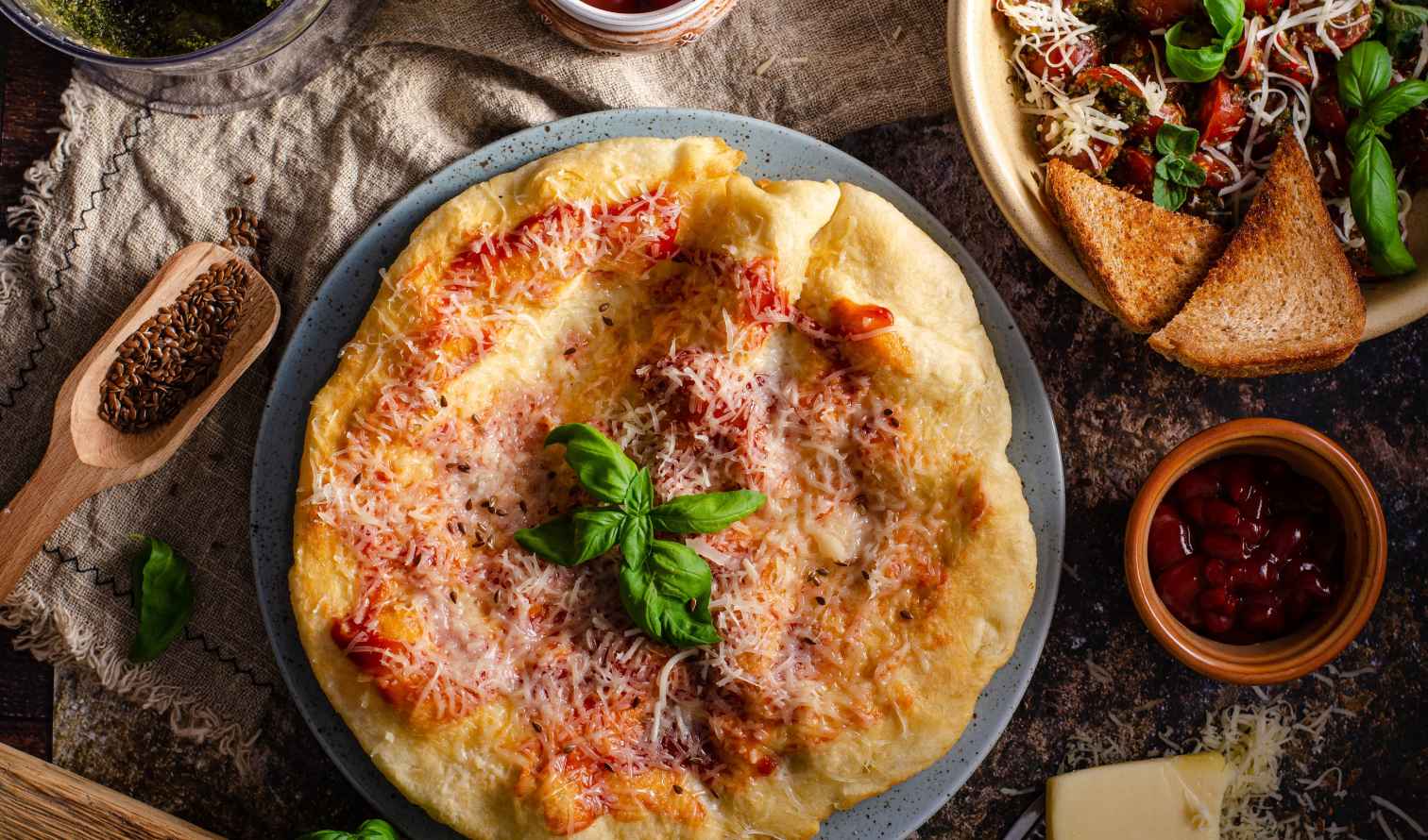 Pizza topped with cheese and basil next to a salad and bread in Budapest