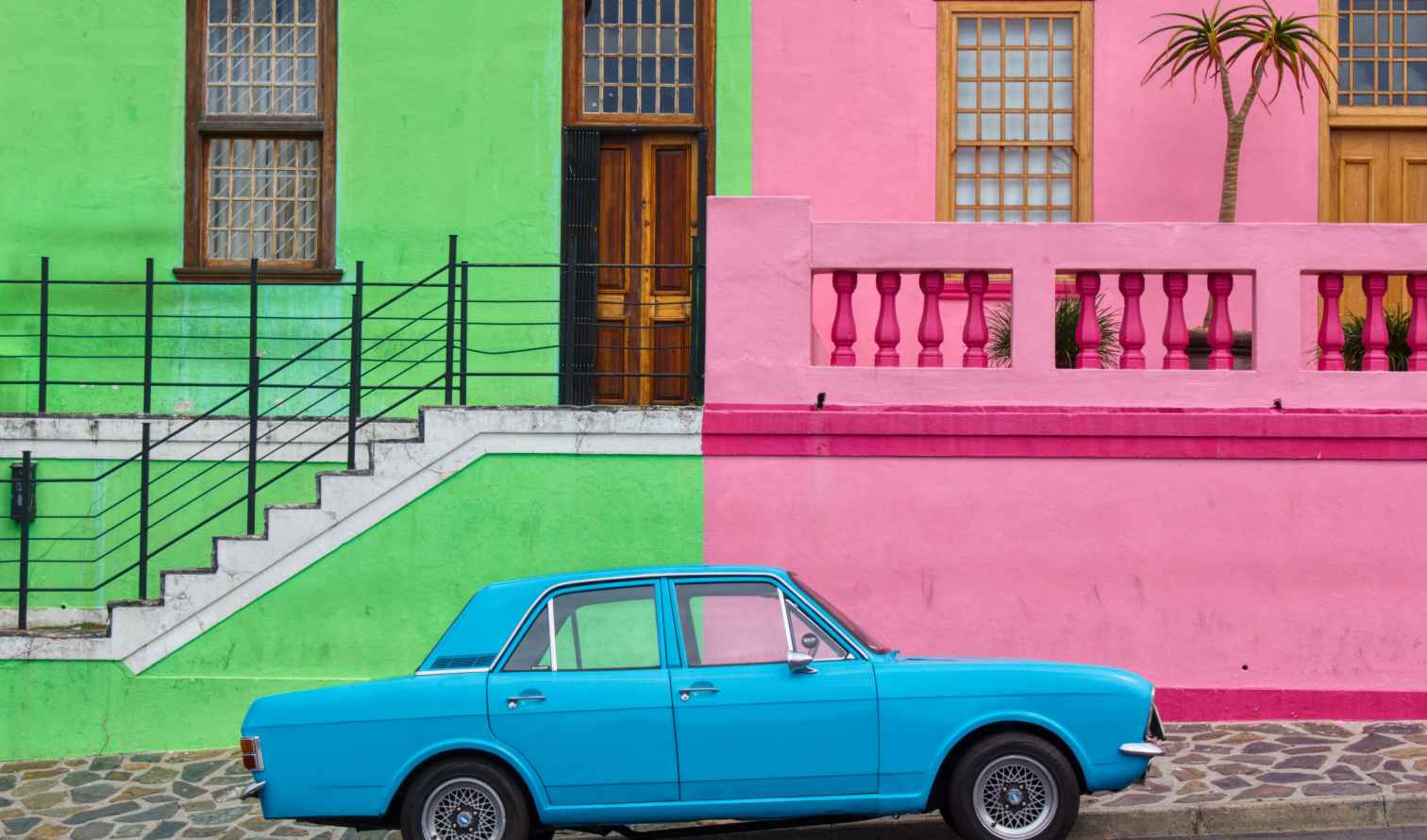 A blue car parked in front of colorful houses in Bo-Kaap, Cape Town.
