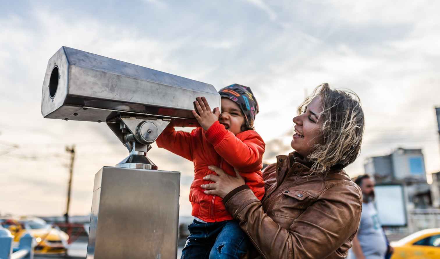 City street view with a woman and child looking through a telescope in Istanbul