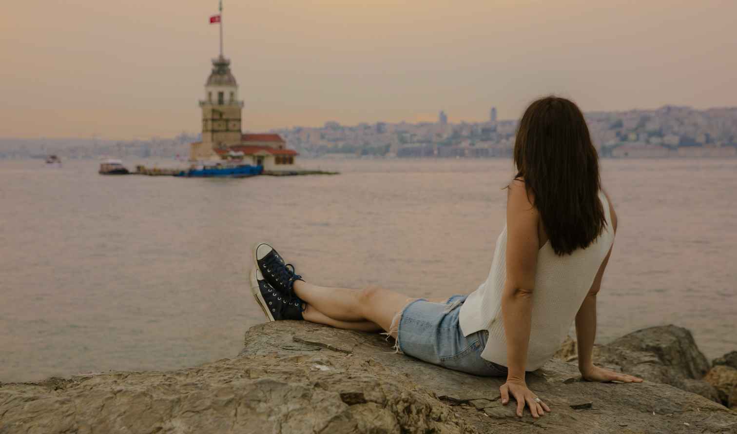 Individual sitting on a rock facing Maiden's Tower across the water in Istanbul
