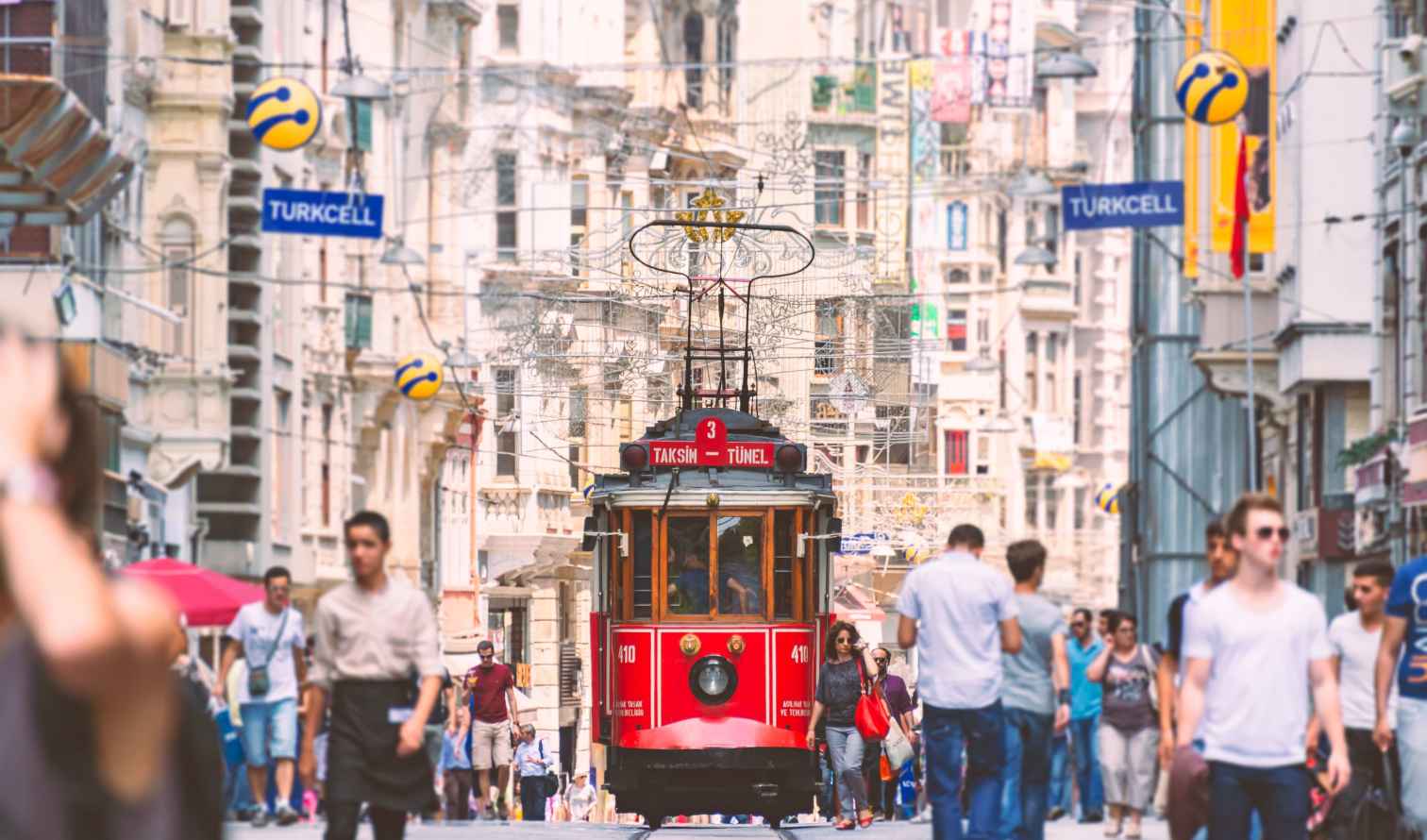 Street-level view of a red tram traveling through Istiklal Street in Istanbul, Turkey.