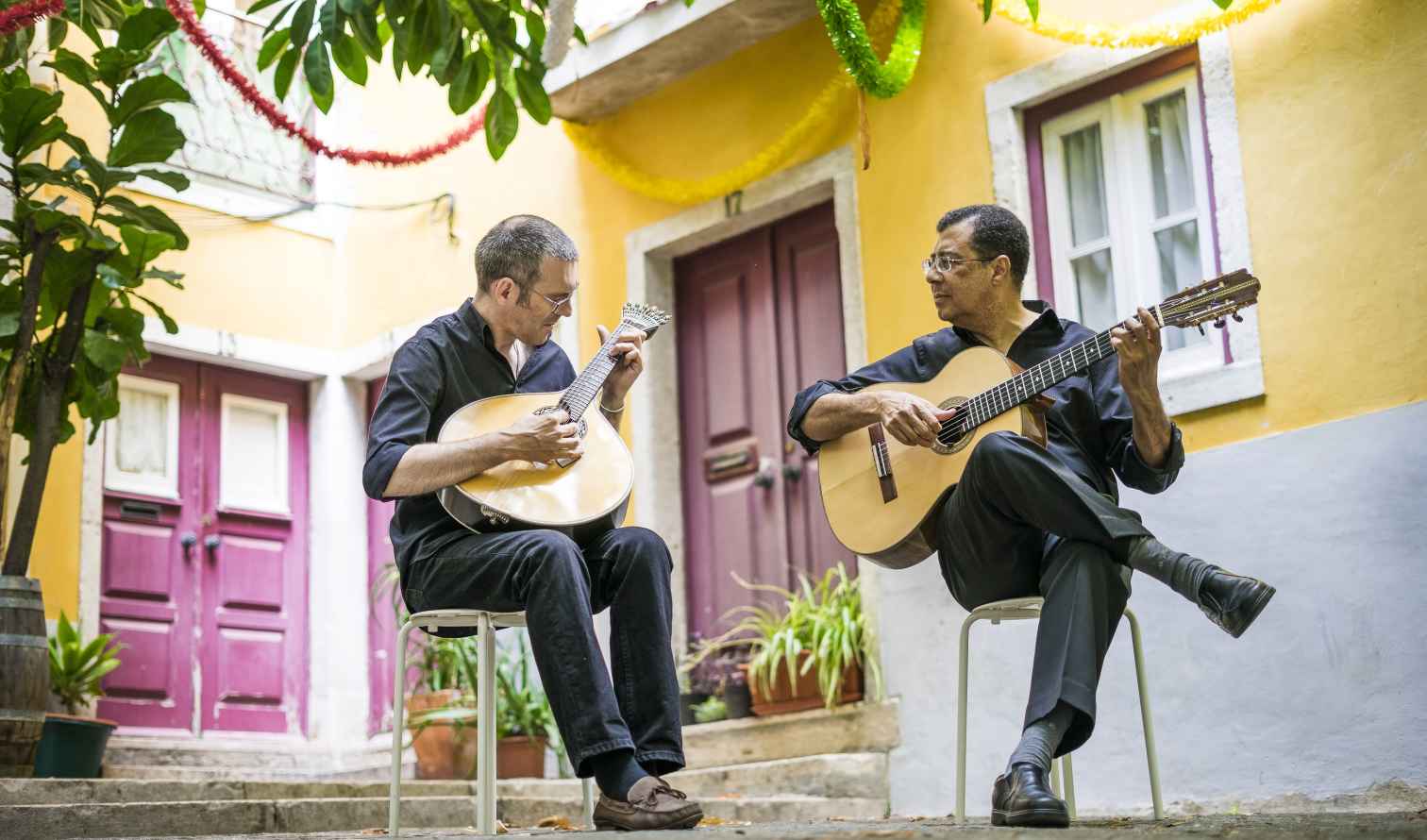 Guitarists performing in a small yellow courtyard in Lisbon, Portugal.