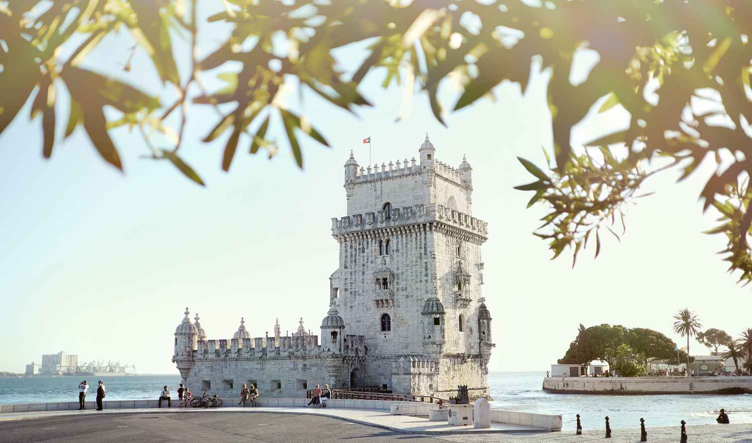 People sitting and walking near the riverside at Belém Tower, Lisbon.